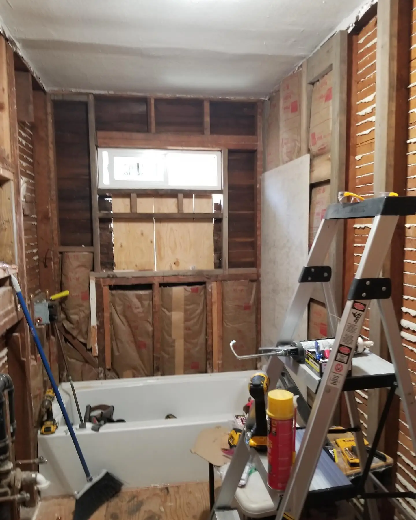 Bathroom taken down to the studs before remodeling, showing framing and rough plumbing